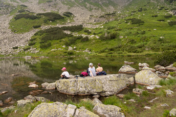 three young tourists resting by a mountain lake