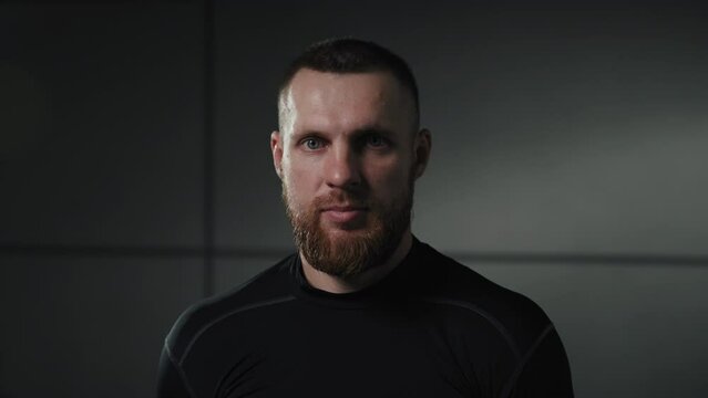 A man's flesh against a gray wall. The athlete looks at the camera.
