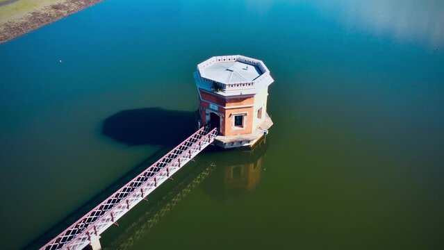 Aerial 360-degree view of a tranquil lake surrounding a tower with a bridge in spring