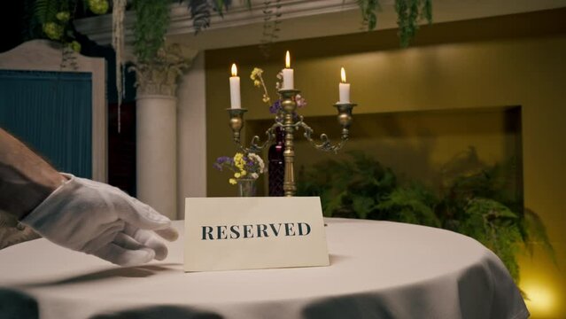 Close-up of a waiter placing a reservation sign on a table in an expensive luxury Italian restaurant