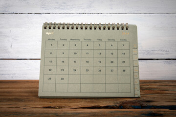 APRIL 2024 cardboard desk calendar and planner on a wooden texture table