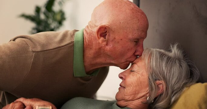 Bed, sick and senior couple kiss forehead for support, bonding and compassion together at home. Retirement, marriage and elderly man and woman embrace in bedroom for illness, healing and recovery