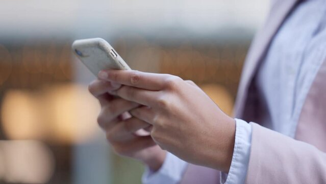 Businesswoman texting an email on her phone outside in an urban city. Closeup of a trendy female posting online on social media. Lady writing or sending important message on a messaging app outdoors