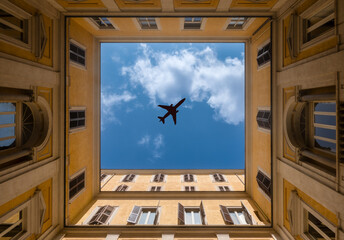 airplane flying in the sky over the city. View from down to the top. High angle perspective. Plane flies over roof of building, house roofs. Window into sky