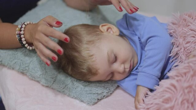 Woman healer performing access or consciousness bars to young boy, a pseudoscientific method of alternative medicine that focuses on massaging various points on the head, alternative medicine concept