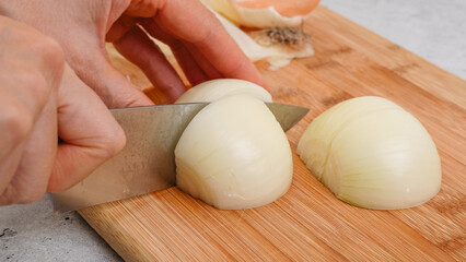 Peeling and cutting white onion on a cutting board. Vegetable soup recipe. Ingredients close-up