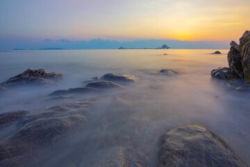 Long exposure of a sunset over the rocky sea.