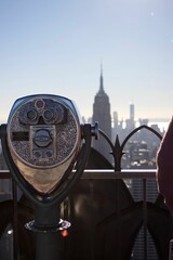 Vertical shot of a coin-operated binocular with a background of the Manhattan cityscape