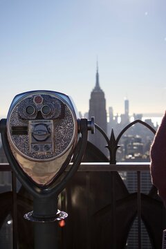 Vertical shot of a coin-operated binocular with a background of the Manhattan cityscape © Wirestock