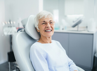 Portrait of a beautiful senior woman in elegant glasses with healthy smile sitting at the dental office. Joyful elderly lady in the clinic. - obrazy, fototapety, plakaty