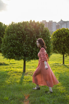 Full length image of a girl in a park dressed a beautiful orange dress, walking in the park.