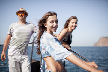 A group of friends are resting on a boat against the background of the sea and island © Вероника Зеленина