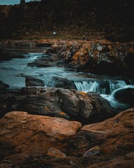Vertical of a cascade flowing through rocks on a cloudy day shot in long exposure © Wirestock