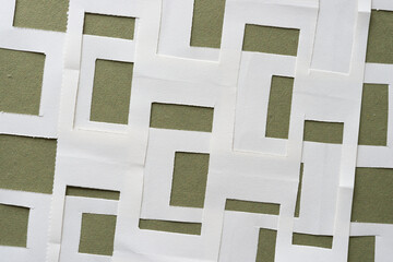 blank paper with rectangle cutouts arranged in a layered form on rough green paper