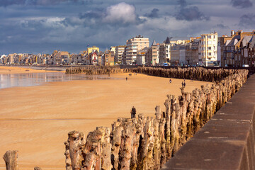 High stone embankment and beach at low tide, in beautiful Saint-Malo, Brittany, France - obrazy, fototapety, plakaty