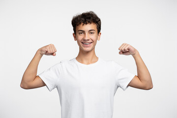 Portrait smiling strong teenage boy wearing stylish white t shirt showing muscles looking at camera