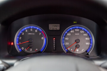 Car dashboard with red instrument circles with backlit arrows at night with a speedometer,...