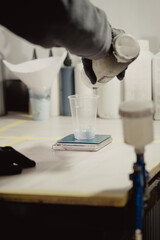 Woman in black protective gloves filling gun with paint in car workshop. Master adds paint to airbrush before before the spraying procedure.