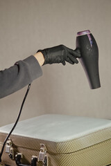 The workplace of the master restorer. Repair of leather goods. Blow-drying of the repair part on a leather suitcase. A hair dryer in women's hands.