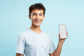 Portrait handsome smiling guy with braces wearing white t shirt holding mobile phone, blank screen