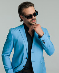 sexy bearded businessman with sunglasses holding hands in pockets and looking to side