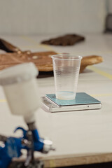 Tools and materials for repair and restoration leather on the table with bag in background. Focus on plastic cup