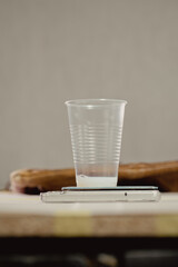 A plastic cup stands on a scale with paint for the restoration of a leather bag. The bag in the background