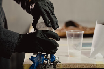 The workplace of the master restorer. Tightening the spray gun cover. Spray gun without hose with...