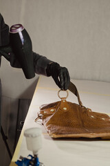 The workplace of the master restorer. Repair of leather goods. Blow-drying of the repair part on a...