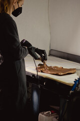 The workplace of the master restorer. Repair of leather goods. Blow-drying of the repair part on a...