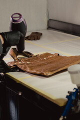 The workplace of the master restorer. Repair of leather goods. Blow-drying of the repair part on a leather bag. A hair dryer in women's hands