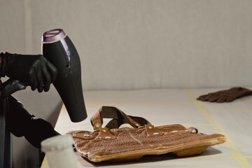 The workplace of the master restorer. Repair of leather goods. Blow-drying of the repair part on a...