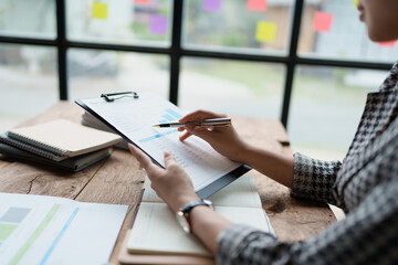 female employee holds a pen and checks investment financial documents.