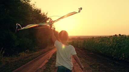 Boy play with toy kite. Son plays, dreams of flying, traveling. Happy boy runs along country road,...
