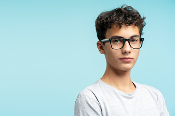 Portrait of attractive serious guy wearing eyeglasses looking at camera isolated on blue background - obrazy, fototapety, plakaty