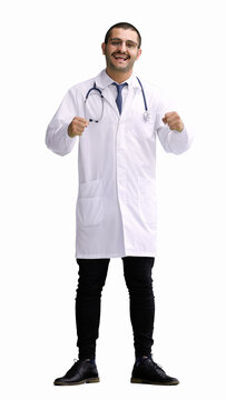 Male Doctor In A White Coat On A White Background Rejoices. Raised His Hands Up