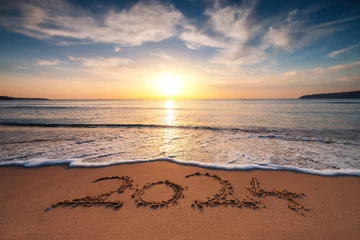 Fotobehang Happy New Year 2024 concept, lettering on the beach. Written text on the sea beach at sunrise. © ValentinValkov