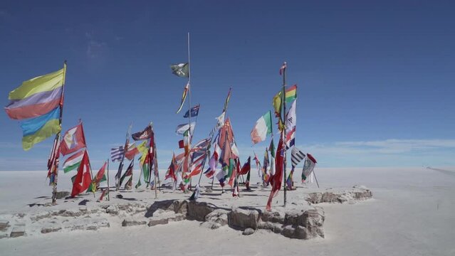 Colorful international flags waving on the Salar de Uyuni close to the Rallye Dakar motor sports event monument in the Altiplano of Bolivia.