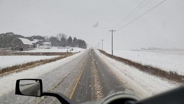 Vehicle traveling dangerously on a snowy road in a rural area during winter in slow-motion