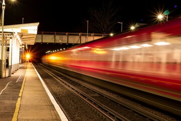 Fototapeta na wymiar Beautiful shot of a fast moving red train at night at a station in London
