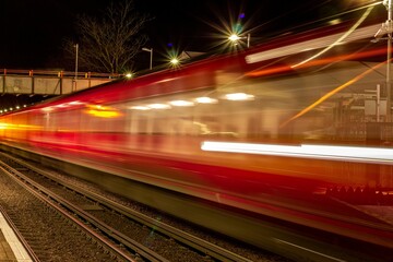 Beautiful shot of a fast moving red train at night at a station in London