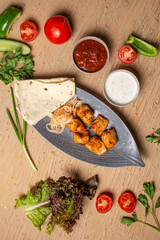 top view of a chicken kebab with sauce in a plate on a table in a restaurant