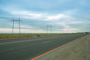 Electric transmission lines along the road in the steppe against the backdrop of the sunset blue sky.