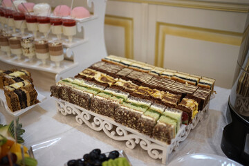 Beautiful and delicious sweet cakes are laid out on the wooden shelves of the buffet table.