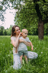 Naklejka na ściany i meble Young woman mom and son play in nature, spend time together and have fun