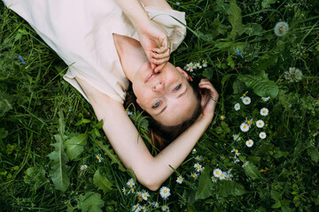 Beautiful woman with natural beauty without makeup lies in the grass in summer
