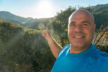 Happy man takes a selfie pointing to the beautiful landscape