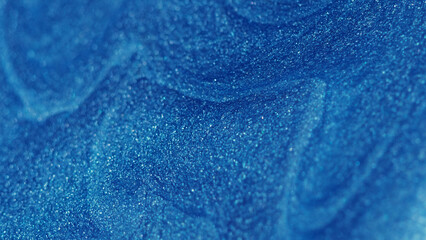 Glitter fluid. Paint flow. Enamel drip. Defocused shiny shimmering blue color wet particles texture...