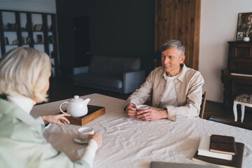Adult man enjoying hot drink with wife in kitchen