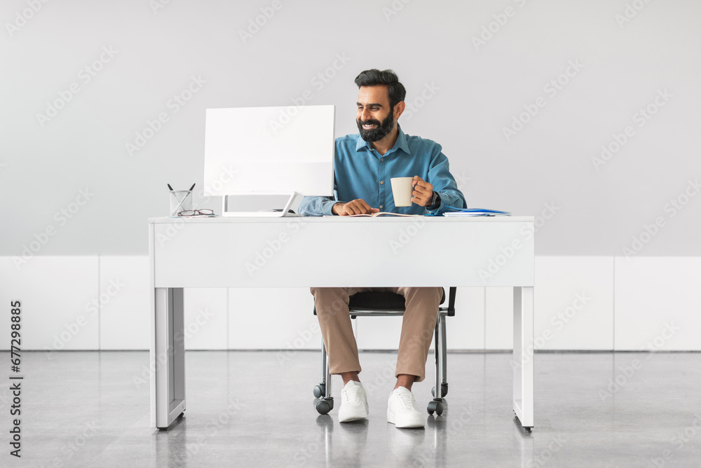 Poster Smiling indian businessman working at computer
